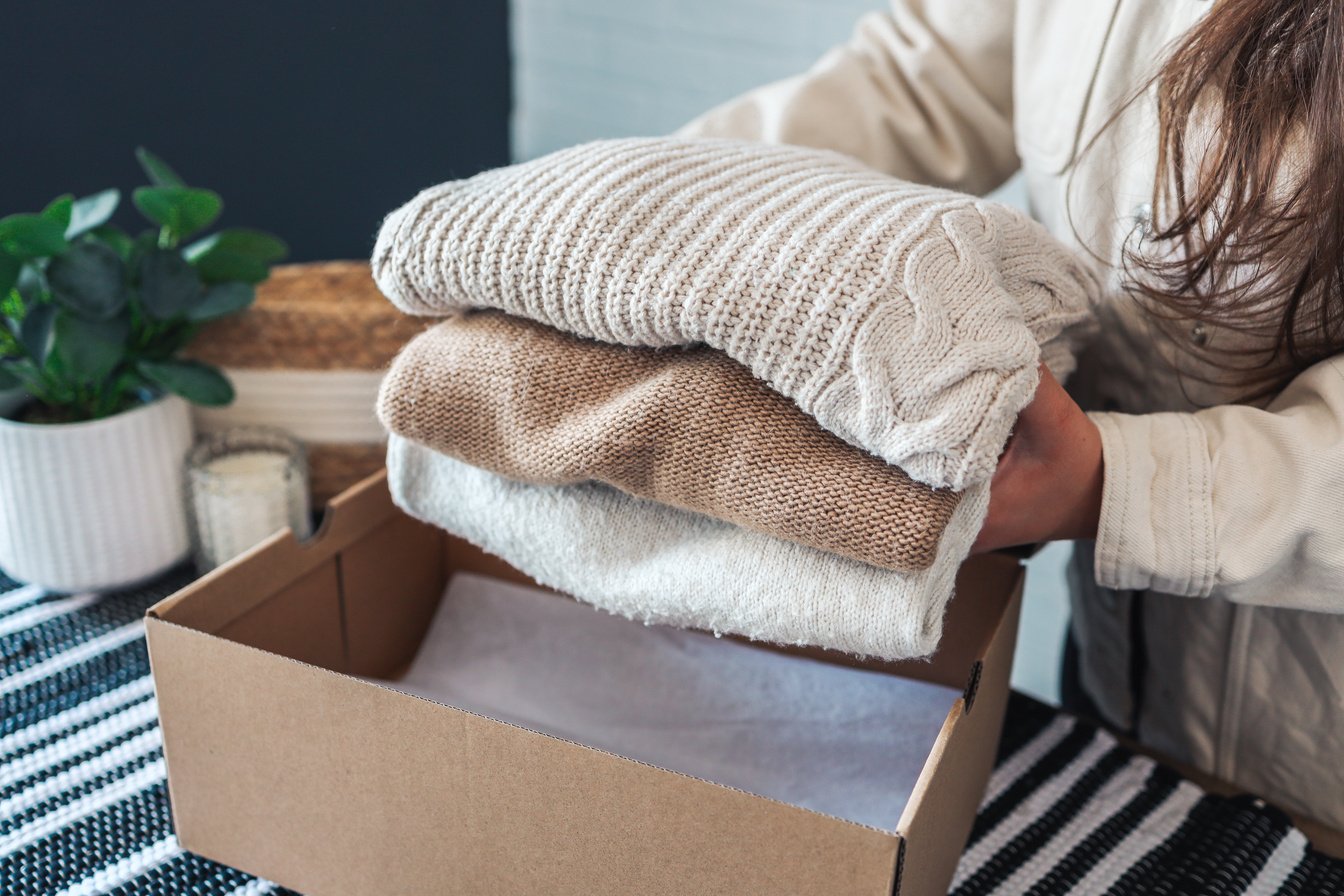 Woman holding Clothes with Donate Box In her room, Donation